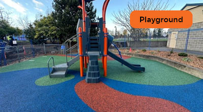 Playground with colourful recycled rubber surface designs in red, blue, and green.